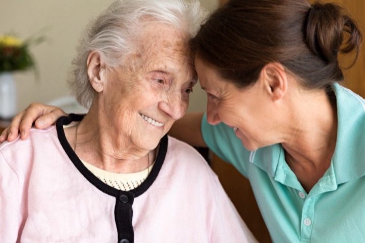 Senior woman smiling at loving woman caregiver who is providing care and support