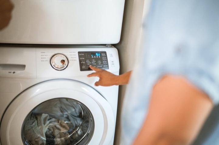 Person pressing the on button for a laundry machine